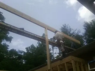Carpenter setting a ridge beam over a new addition frame — Ice Dam Removal by Roofing Brothers in Coal Creek