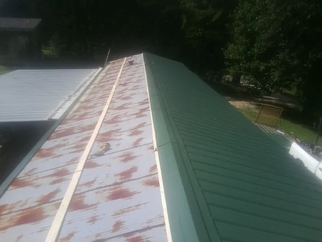 Old rusted panels beside newly installed green metal roofing — Wind Damage Roof Repair by Roofing Brothers in Coal Creek