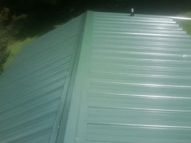 New green metal panels meeting at the ridge of a roof — Flat Roof Repair work by our crew in Coal Creek