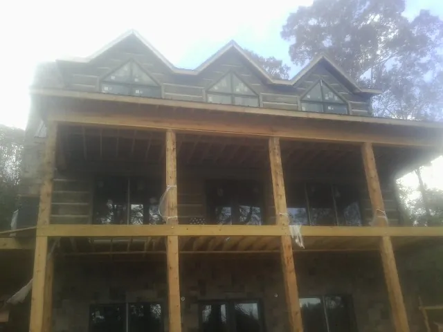 Dormers and porch framing on a large log home under construction — Roof Coating work by our crew in Coal Creek