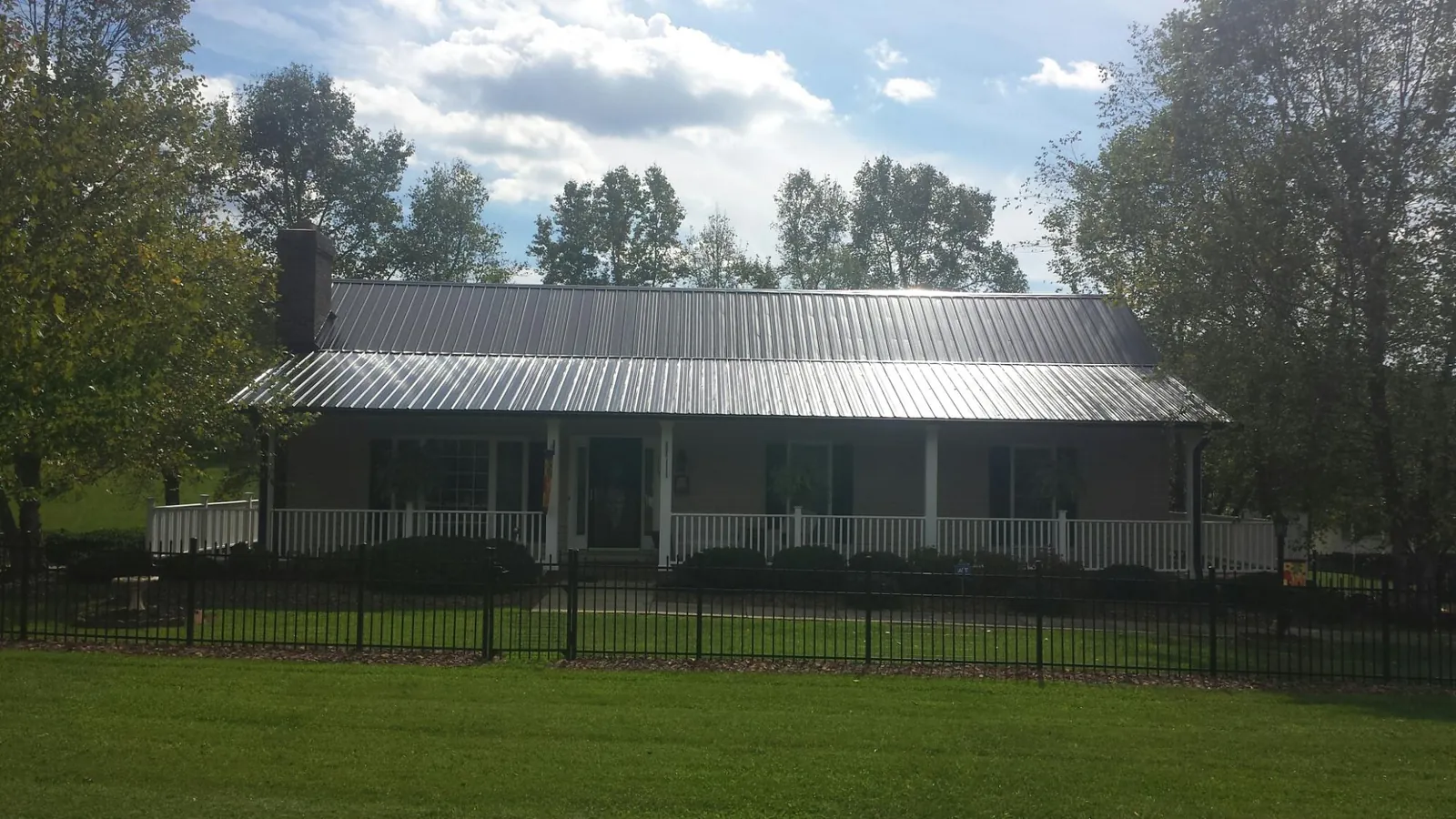 Gray metal roof on a brick ranch with a full width front porch — Gutter Guard Installation work by our crew in Coal Creek