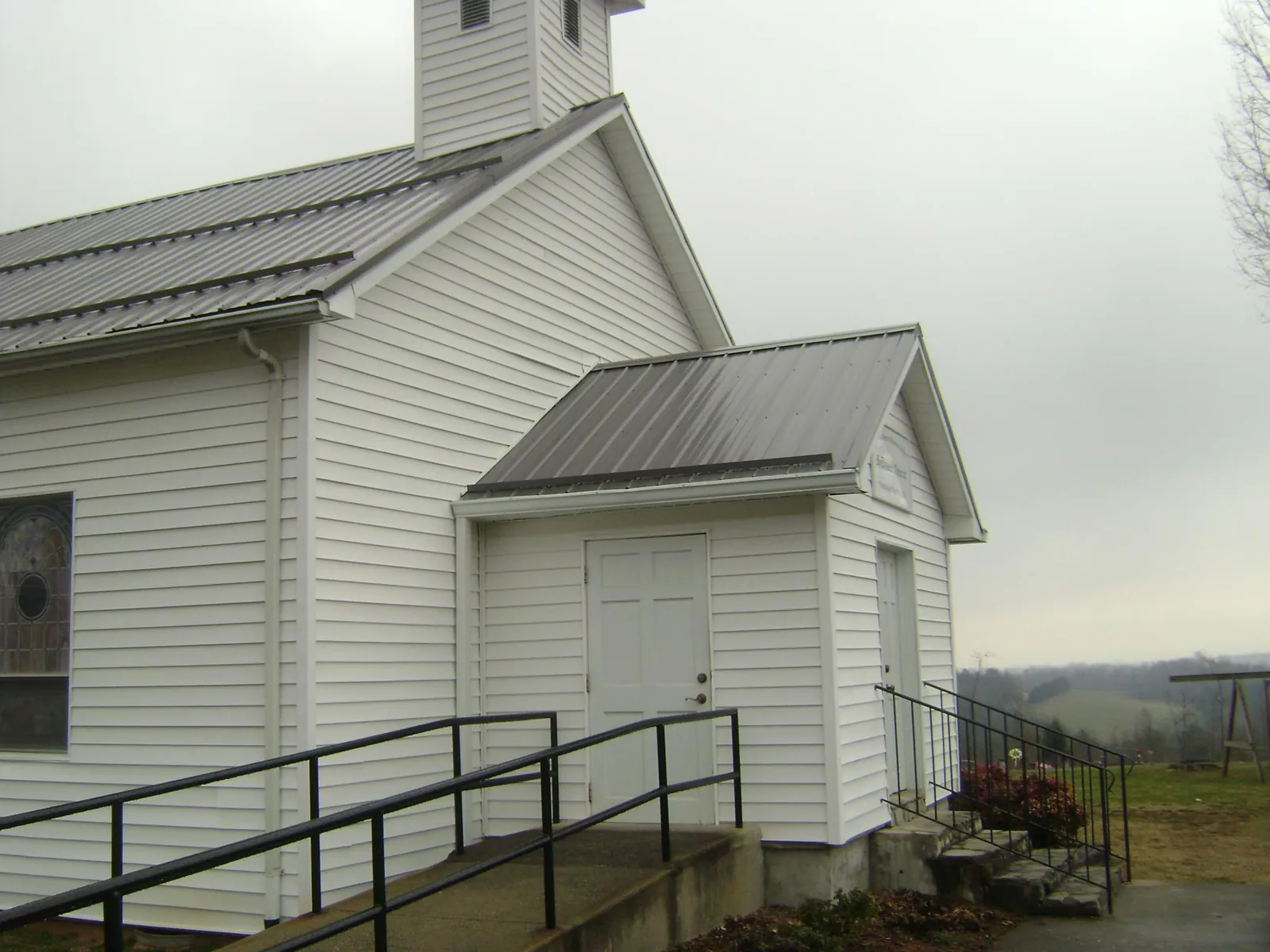 Gray metal roof on a white clapboard church with a steeple in Coal Creek
