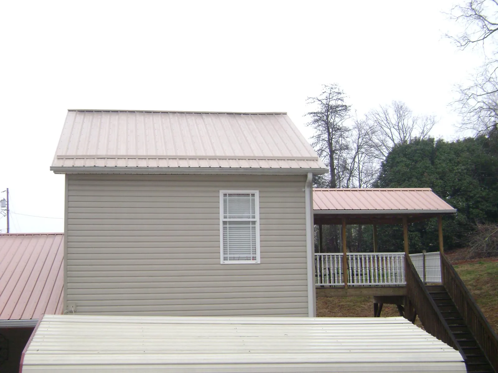 Tan metal roofs on a two story addition and attached porch, from a Roof Replacement job in Coal Creek