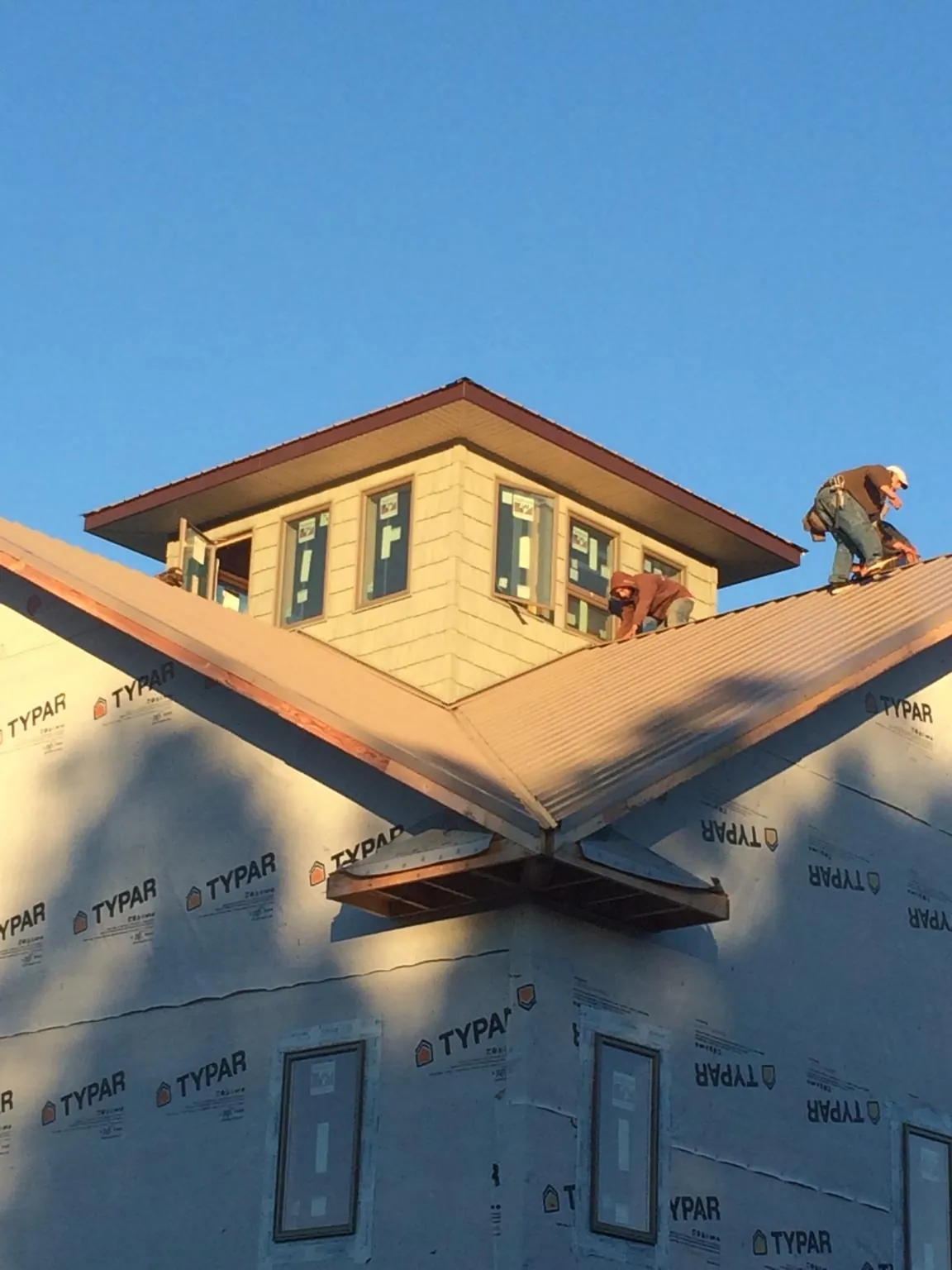 Roofers working around a rooftop cupola on a new metal roof at sunset — Roof Waterproofing in Coal Creek by Roofing Brothers